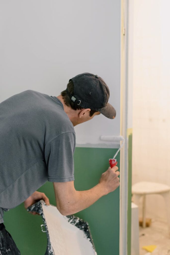pexels-photo-5691597 A man painting walls with a roller during home renovation indoors.
